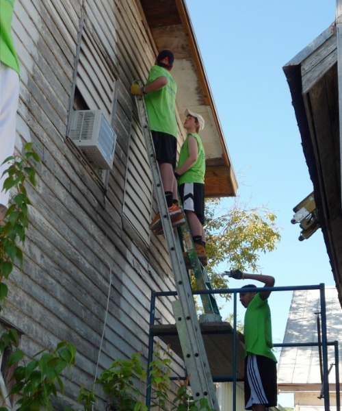 Avon Old Farms School students on a ladder during a Habitat for Humanity trip.